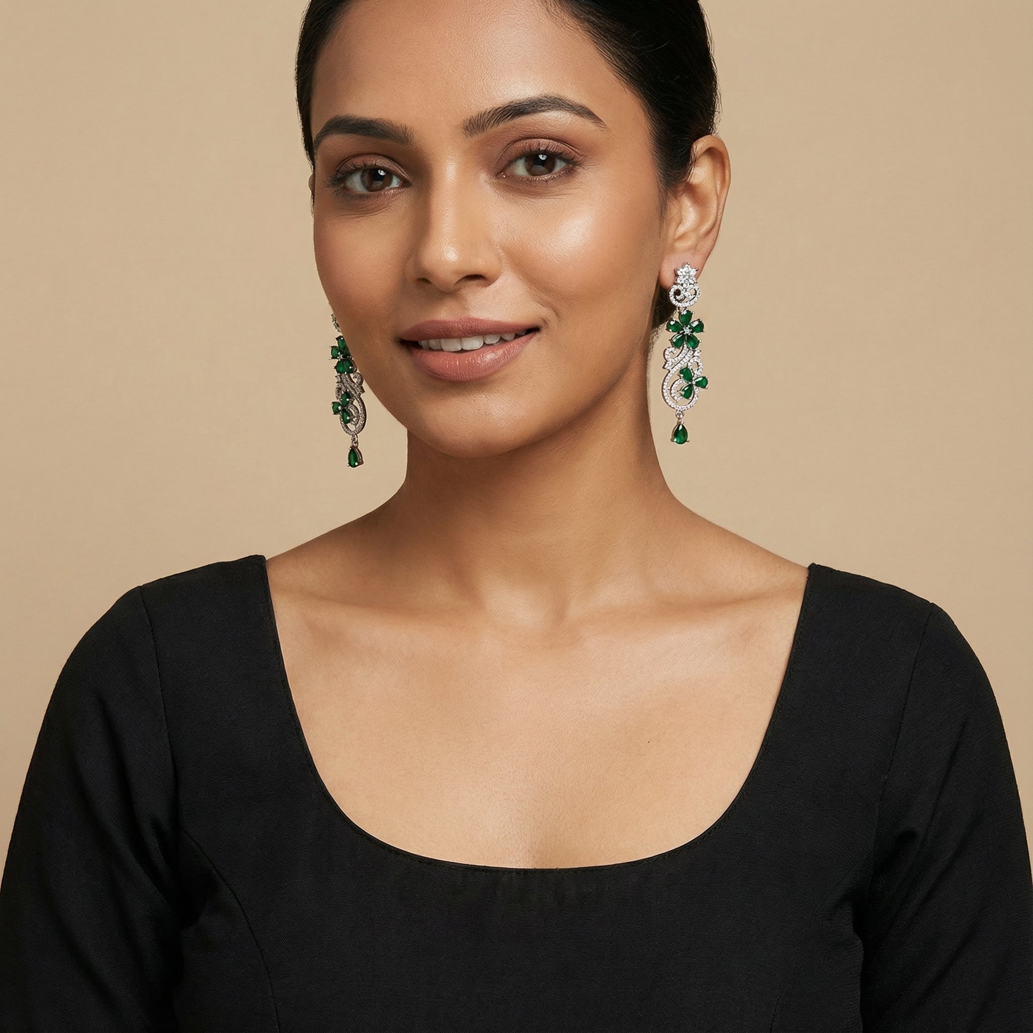 Close-up of Aira Emerald Luxe Earrings showing green stone accents and gold-plated finish