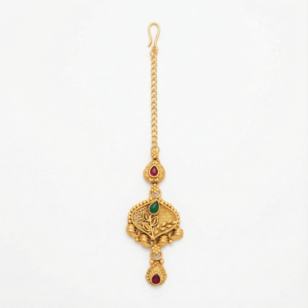 Ishara Leaf Crest Tikka antique gold maang tikka with green and red teardrop stones on gray background