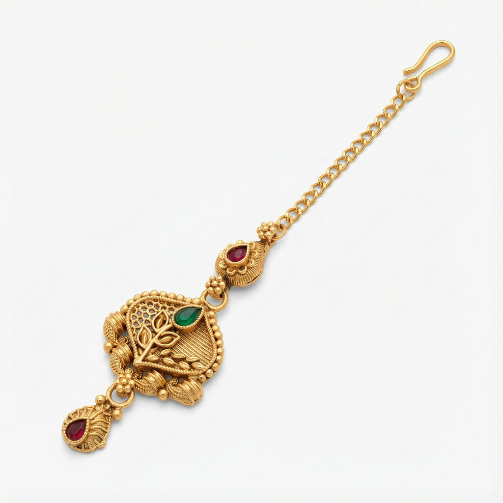Ishara Leaf Crest Tikka detail showing leaf-crest pendant, green center stone, and red teardrop drops