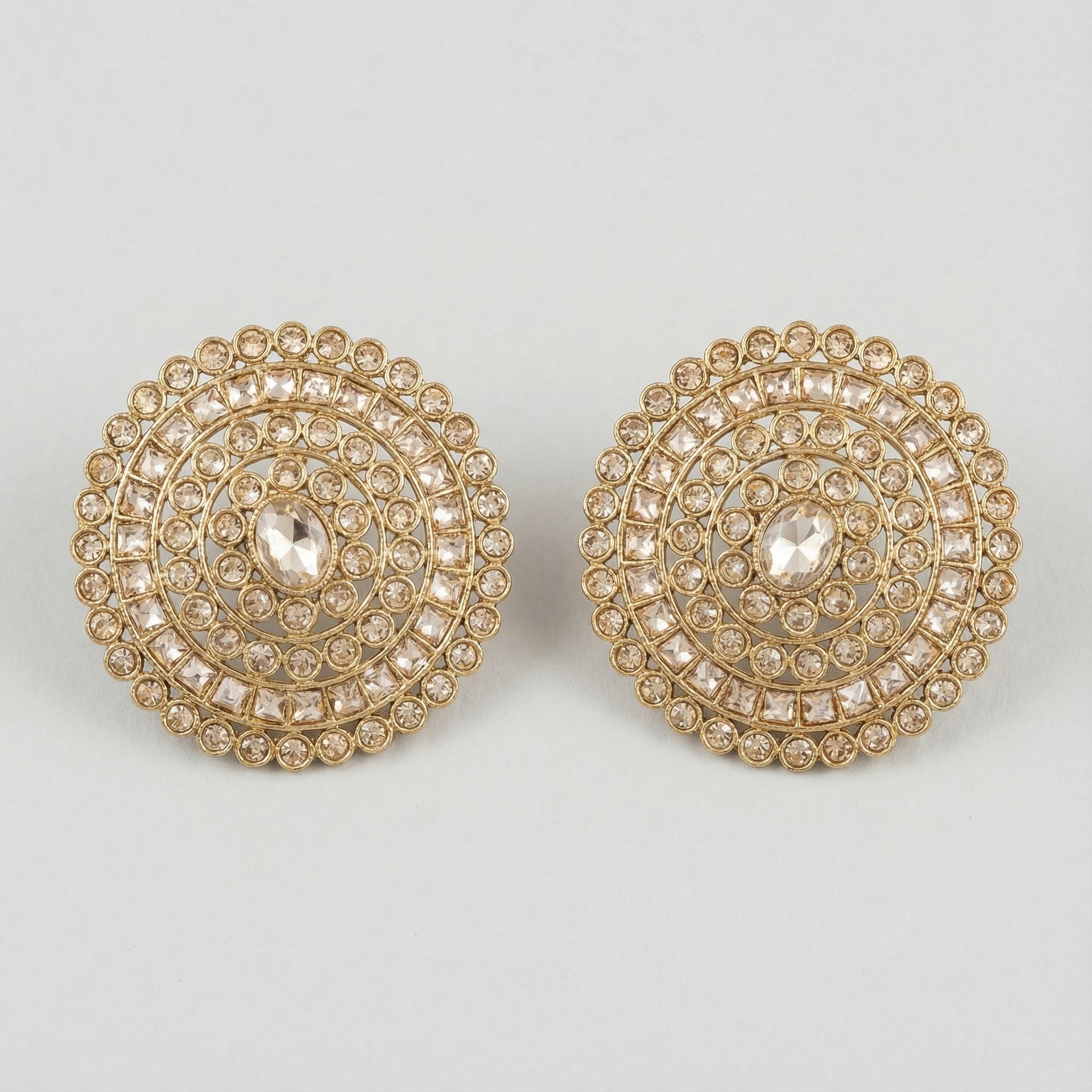 Golden Noor Disc Earrings large gold-tone circular crystal stud earrings on gray background