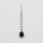 Onyx Halo Drop Tikka silver-tone maang tikka with dark blue teardrop pendant and clear halo on gray background