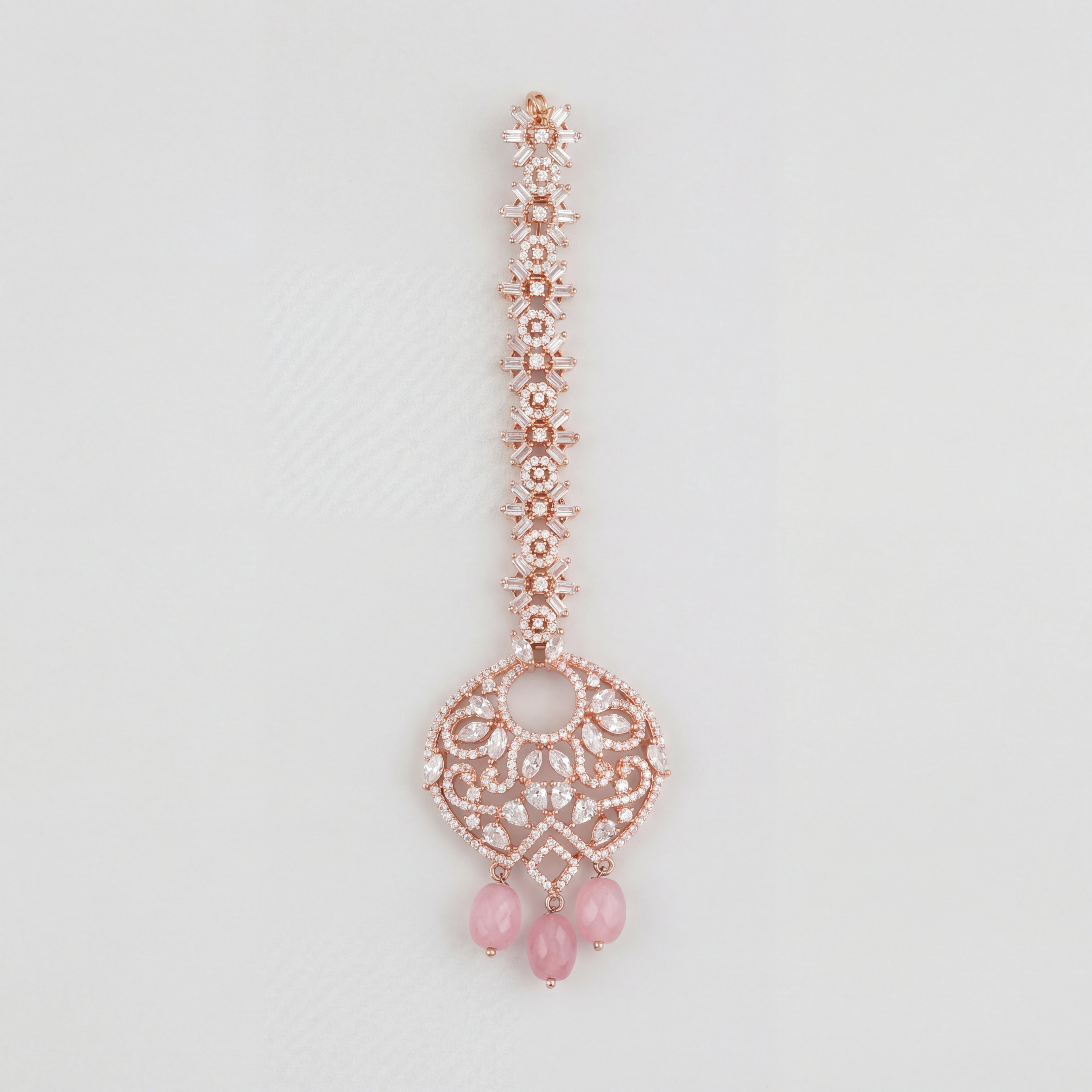Blush Rosette Drop Tikka rose gold maang tikka with filigree round pendant and pink bead drops on gray background