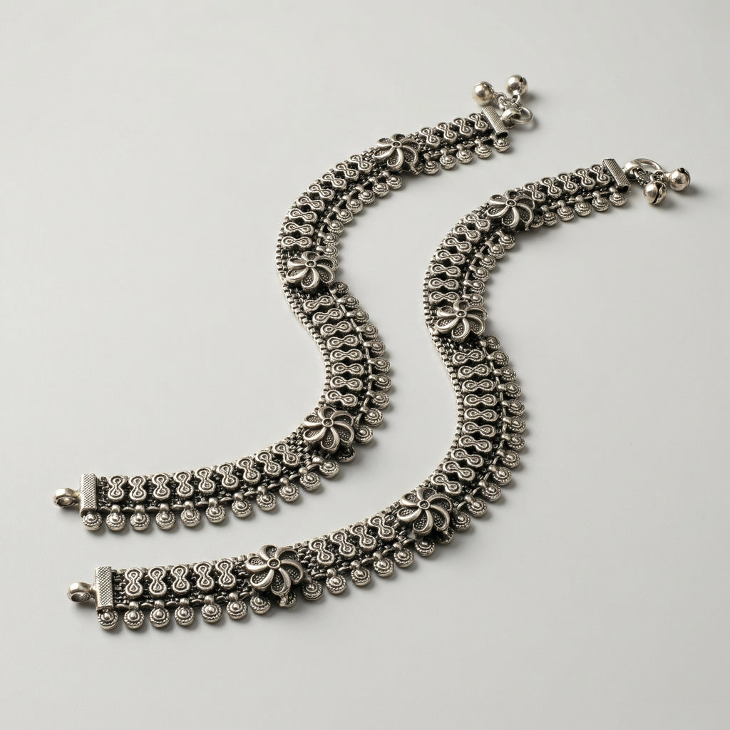 Oxidized Floral Payal pair of antique silver mesh payals with floral motifs and coin charms on gray background