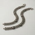 Oxidized Floral Payal pair of antique silver mesh payals with floral motifs and coin charms on gray background