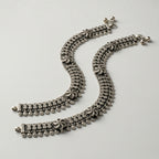 Oxidized Floral Payal pair of antique silver mesh payals with floral motifs and coin charms on gray background