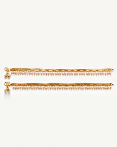 Matching pair of Priya Pearl Anklets laid flat, gold-tone chain with off-white pearl drops and tiny bells
