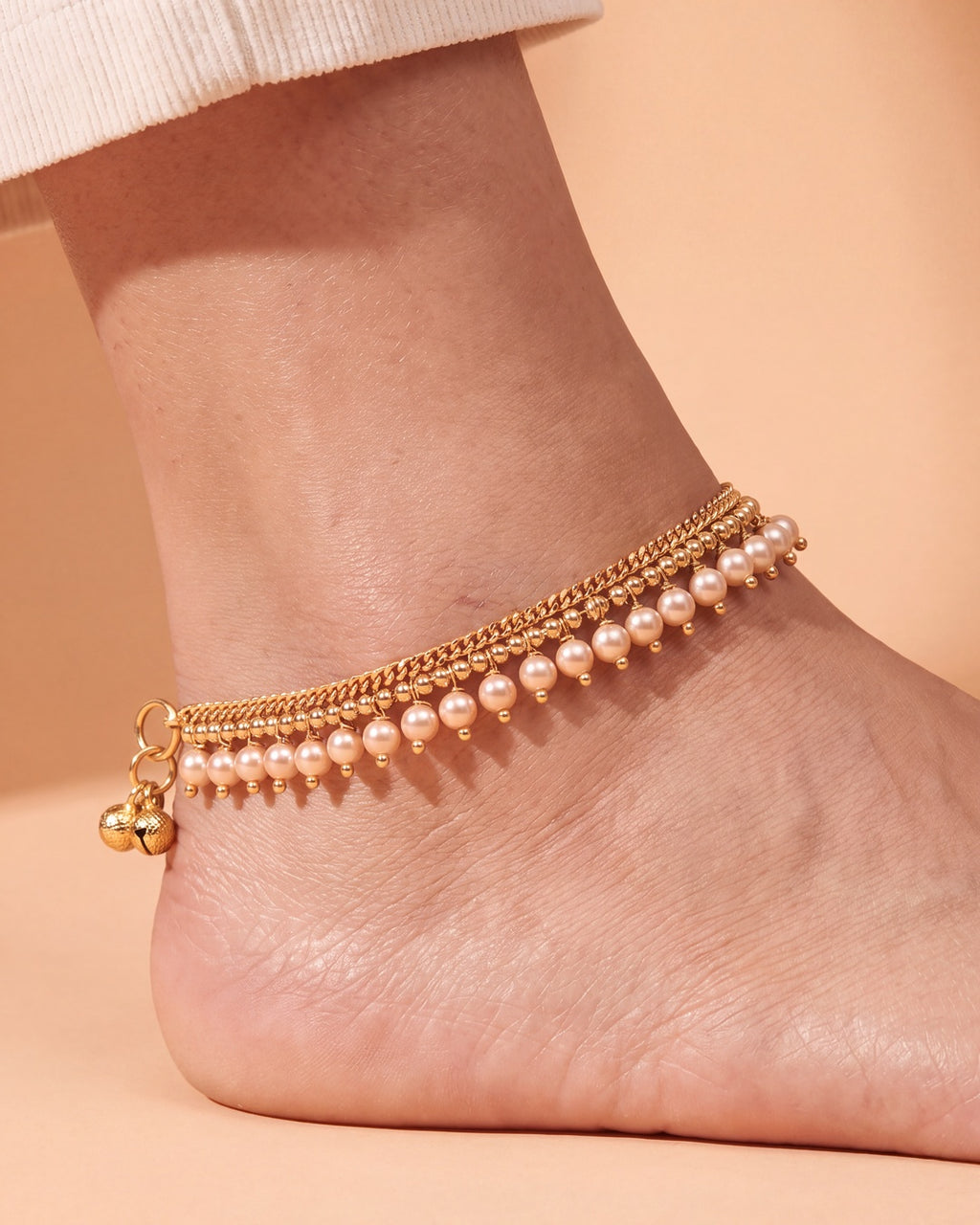 Close-up of a Priya Pearl Anklet on the ankle, double gold-tone chain with off-white pearl drops and tiny bells
