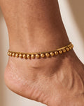 Close detail of Rani Droplet Anklet, gold-tone chain with smooth and textured droplet charms