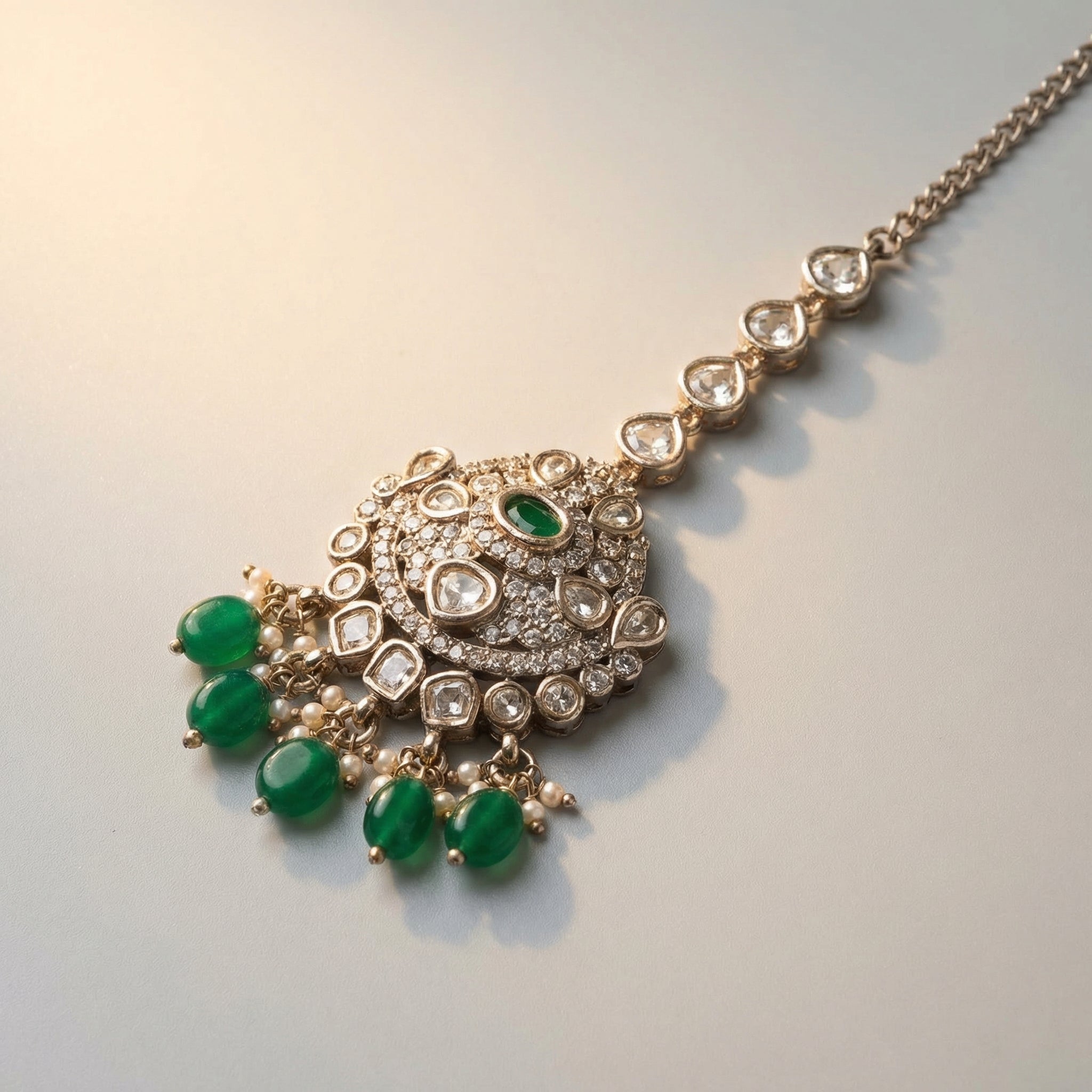 Noor Emerald Tikka detail showing clear crystal chain, pavé circle, and emerald-green drop beads