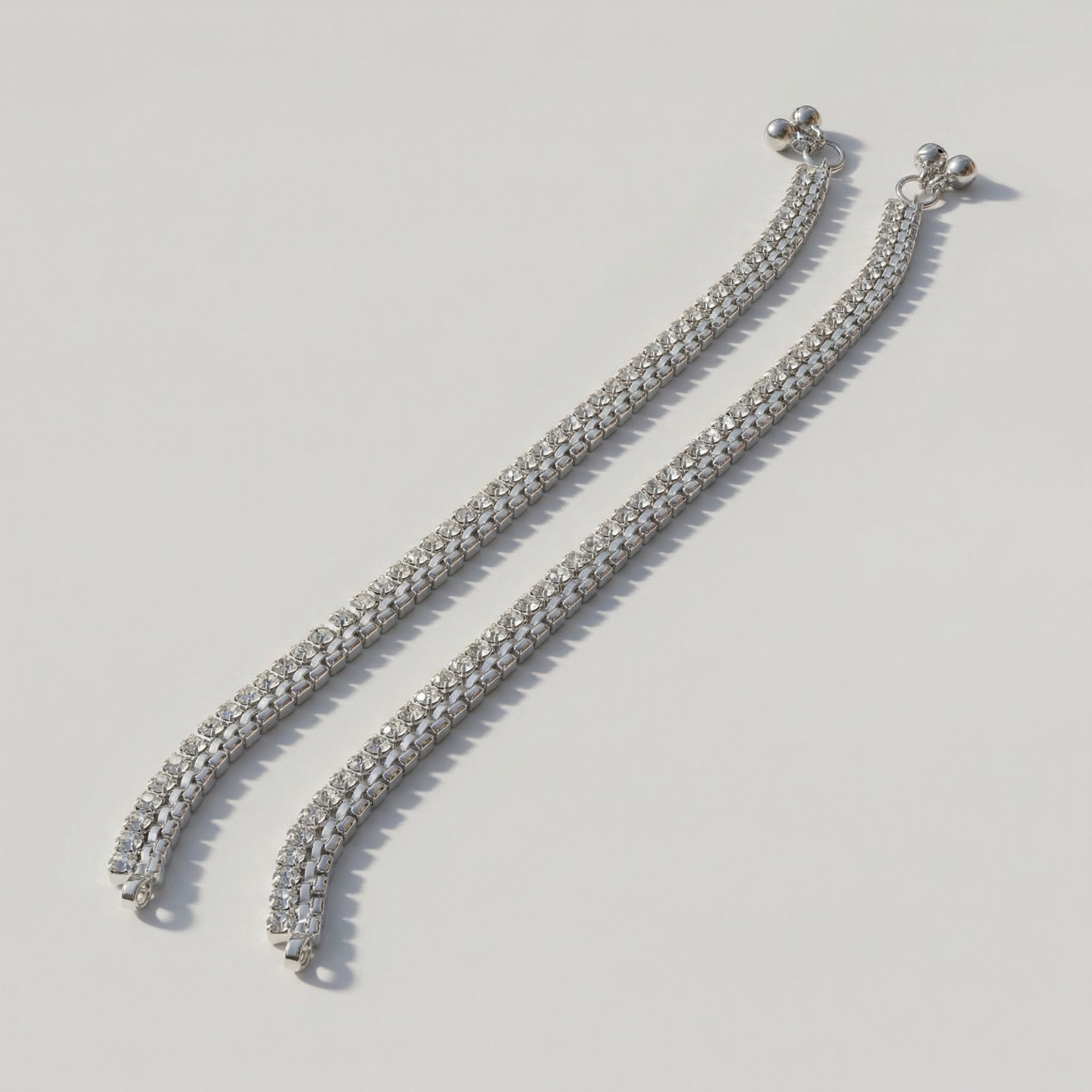 Starlight Anklet pair of silver-tone double-row square crystal payals with ball charms on gray background