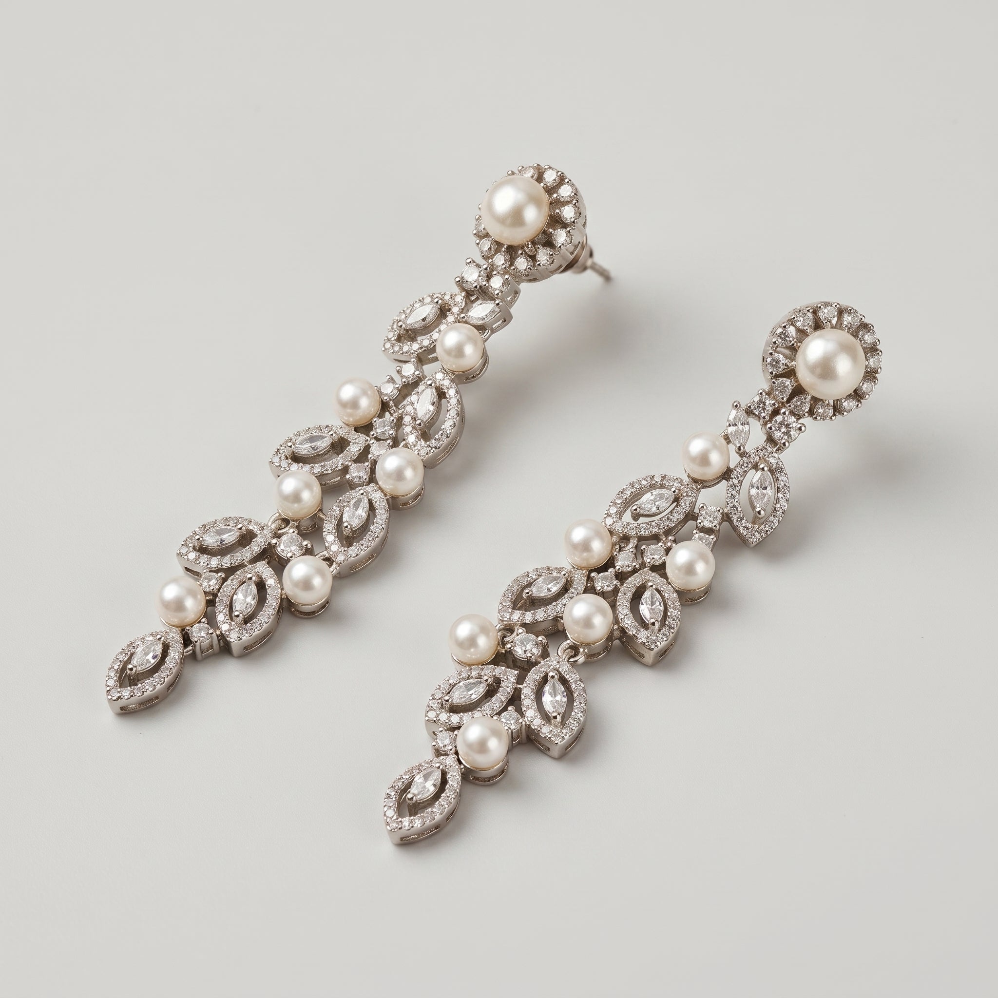 Bela Pearl Earrings detail showing pearl-stud post, cascading leaf frames, and scattered white pearl accents