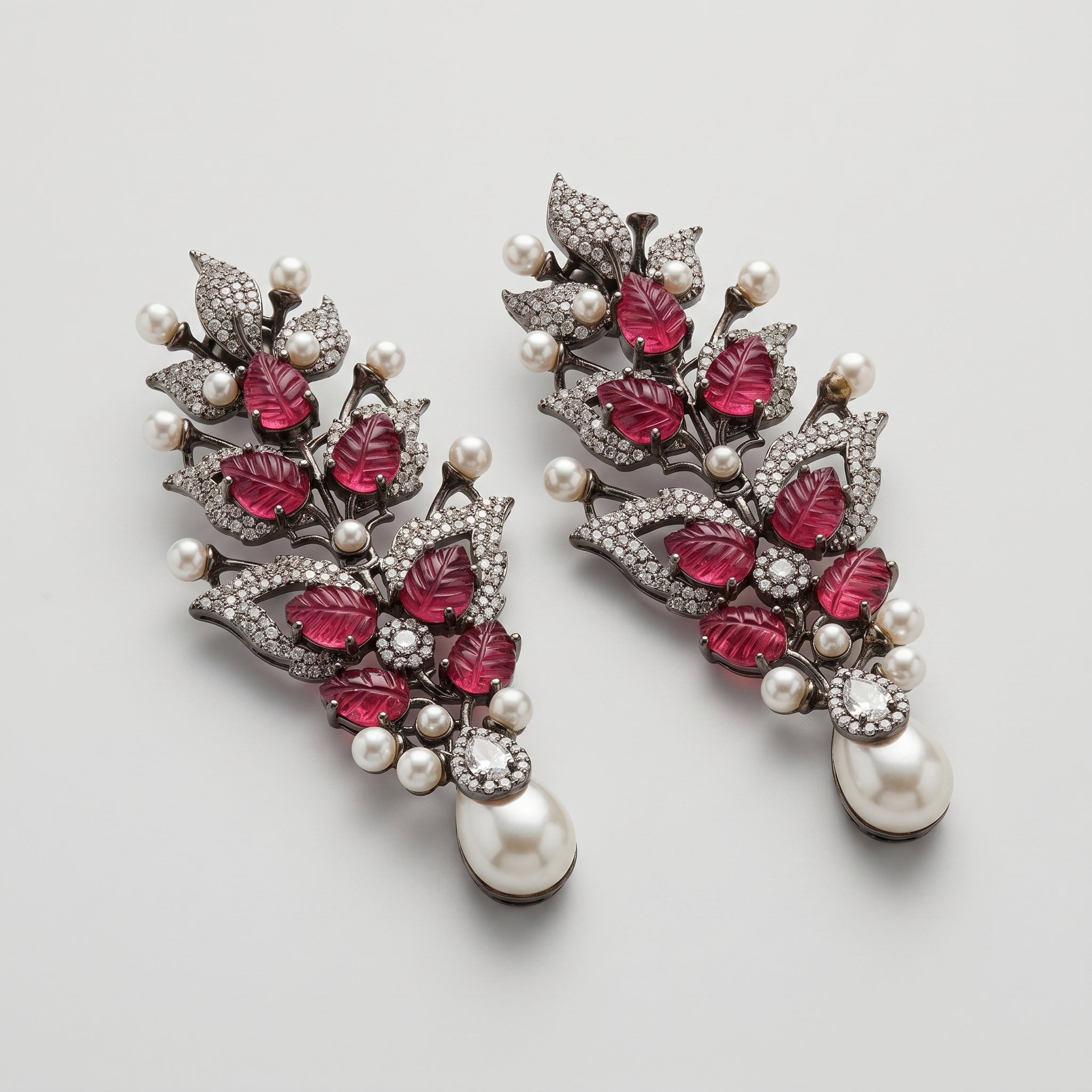 Rani Ruby Earrings detail showing carved ruby-red leaves, clear crystal foliage, and teardrop pearl drop